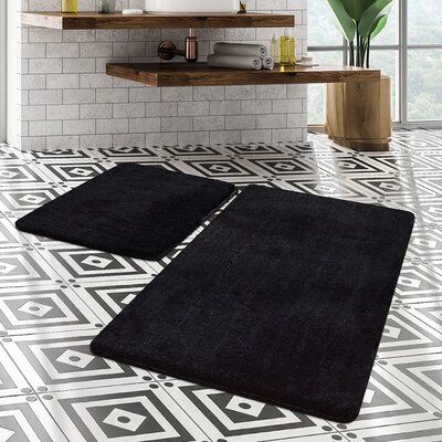 two black rugs sitting on top of a white tiled floor