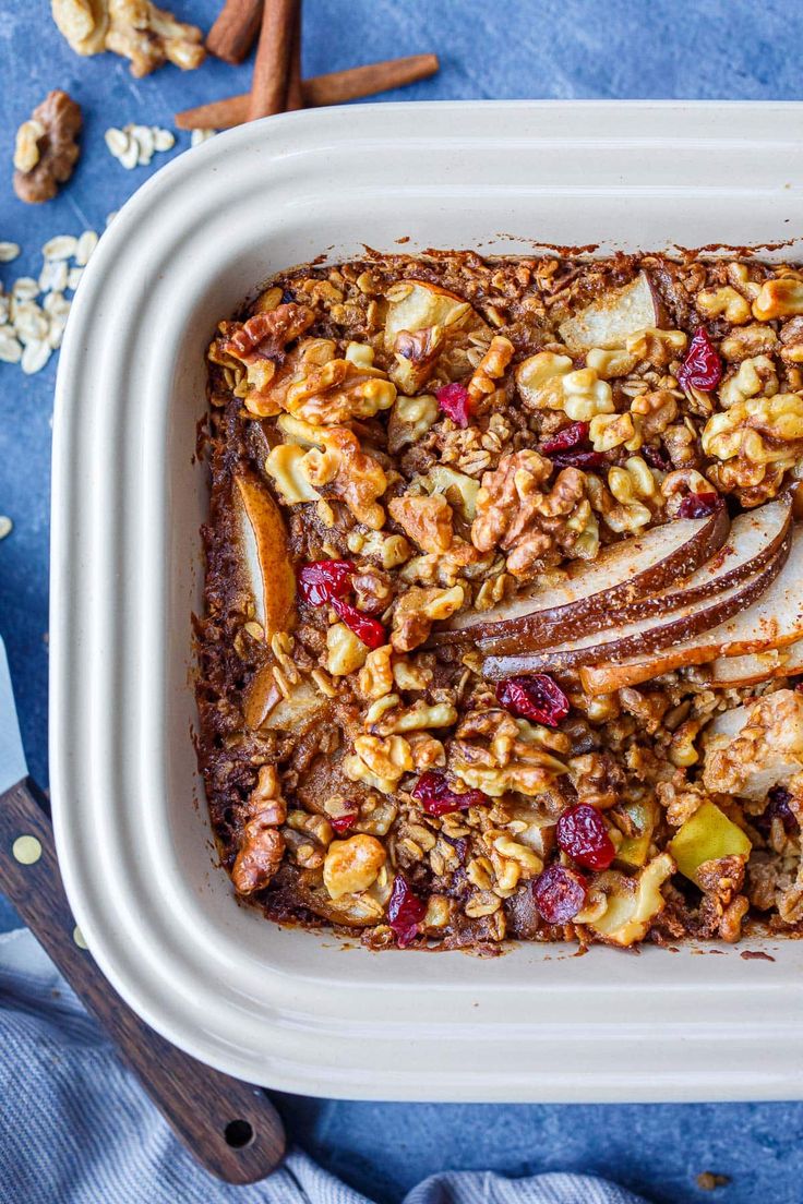 a white dish filled with granola and apples on top of a blue table cloth