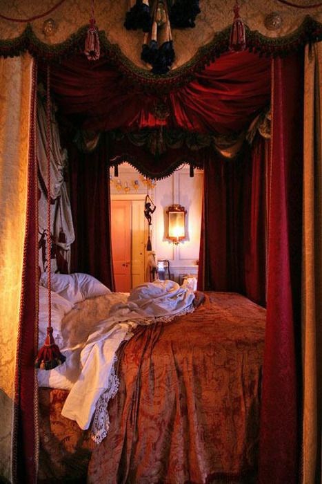 the canopy bed is made up with red drapes