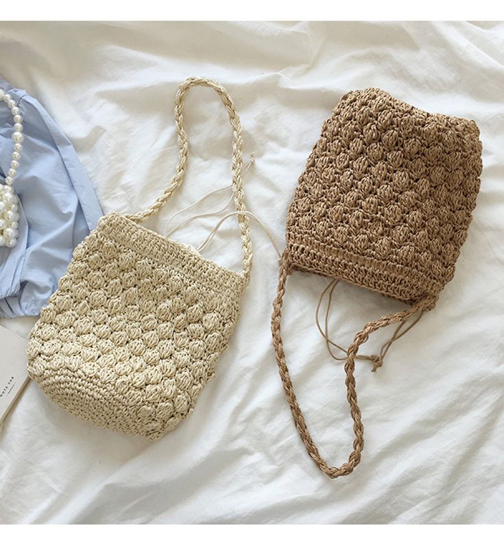 two crocheted purses sitting on top of a bed next to each other