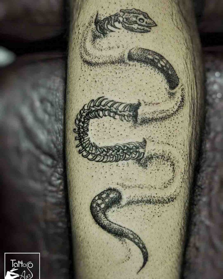 a tattoo on the leg of a man with an image of two snakes in it