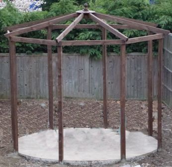 a wooden gazebo sitting in the middle of a yard next to a wood fence