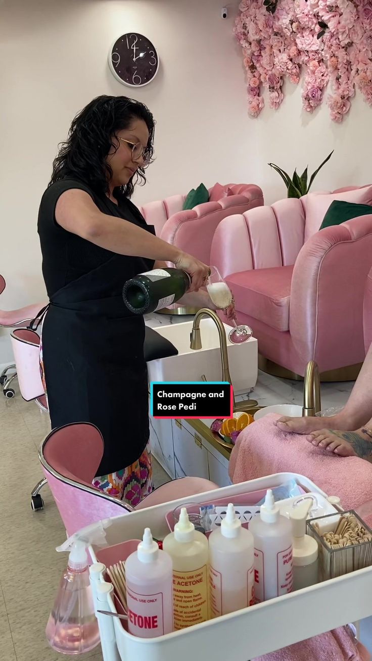 a woman is getting her hair done in a salon with pink chairs and flowers on the wall