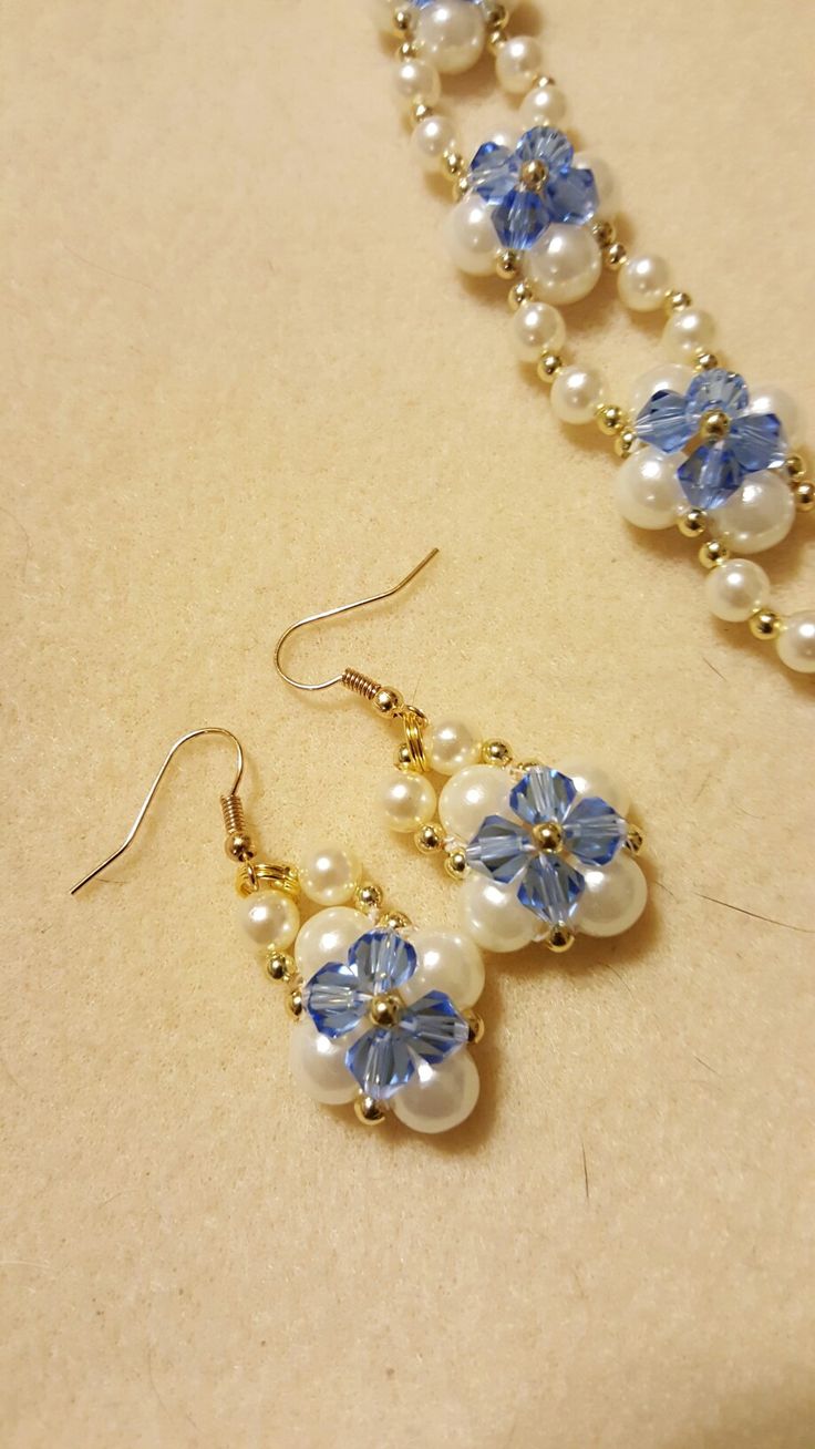 a pair of blue and white beaded earrings sitting on top of a beige surface