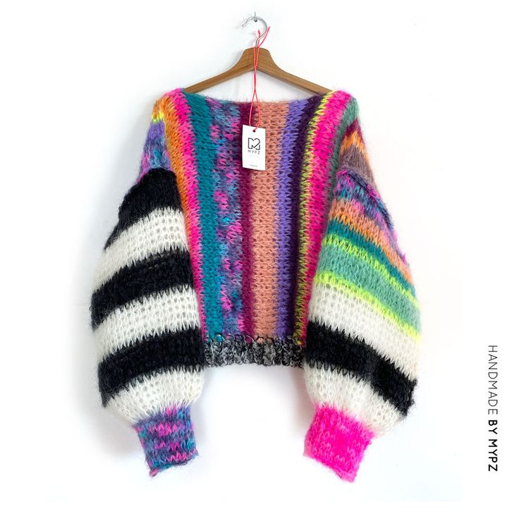 a multicolored sweater hanging on a hanger with a tag attached to it