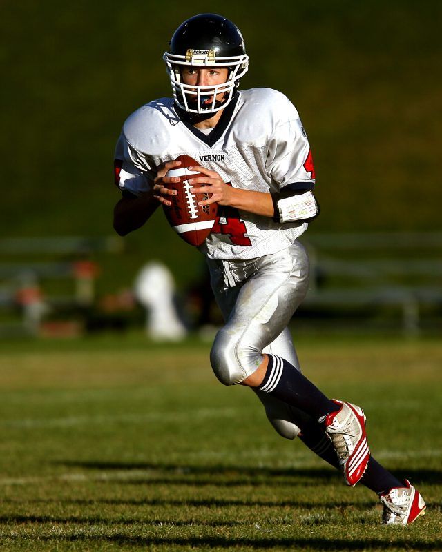 a football player is running with the ball in his hand and wearing a helmet on