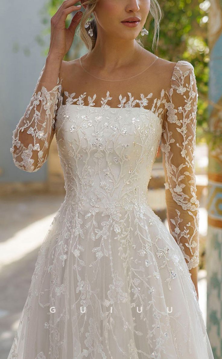 a woman in a white wedding dress with long sleeves and sheer lace on the shoulders