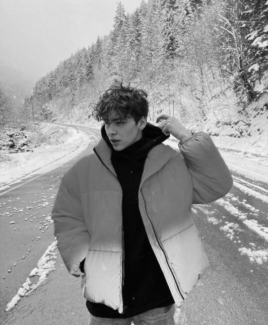 a man standing on the side of a road covered in snow