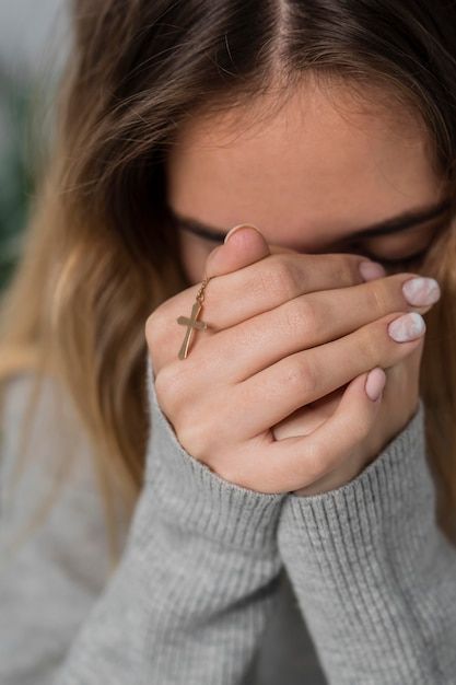 a woman holding her hands to her face with a cross ring on it's finger