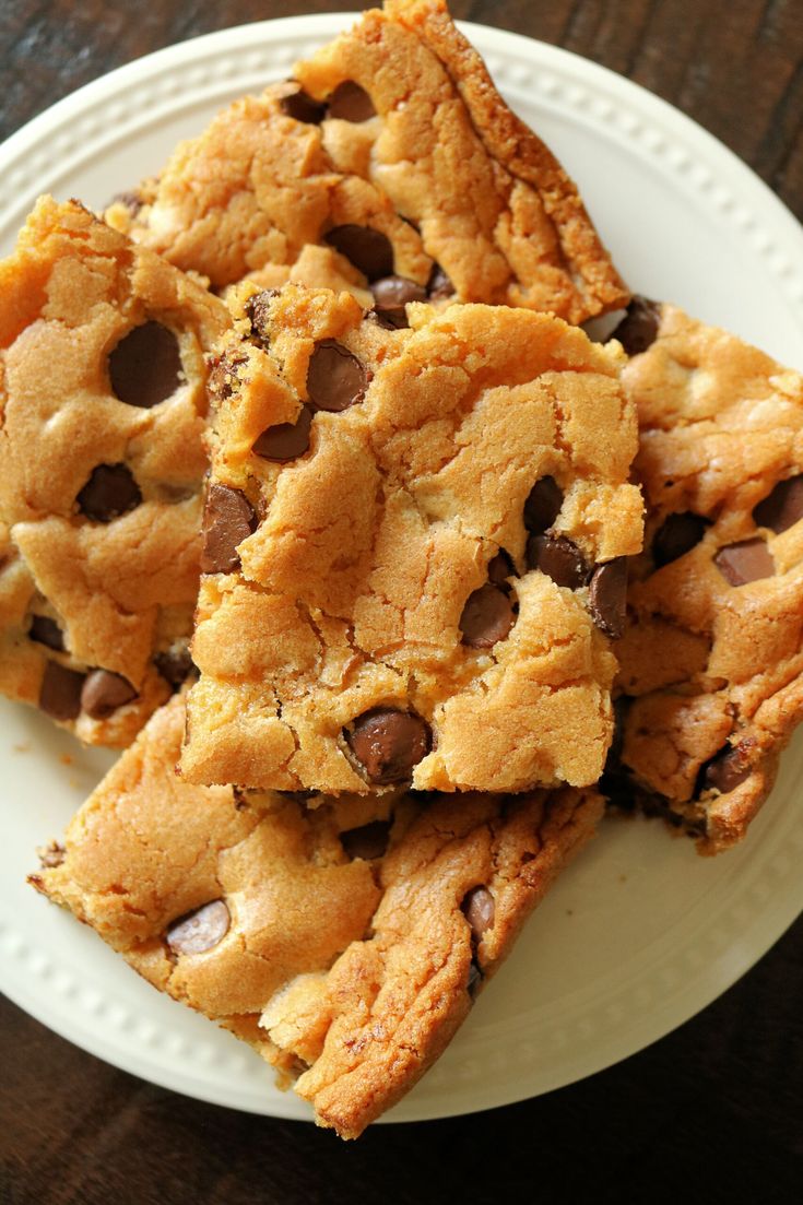 chocolate chip cookie bars stacked on top of each other on a white plate with a wooden table in the background