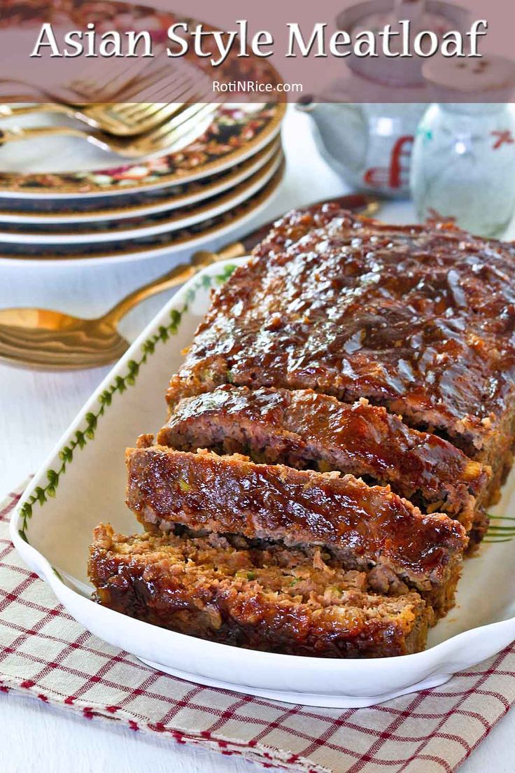 a loaf of meat sitting on top of a white plate next to some forks and silverware