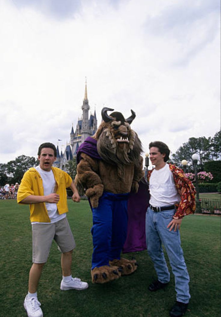 three men standing in front of a castle mascot