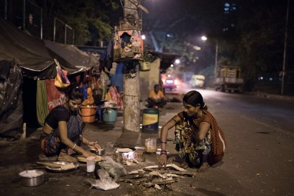 two women are cooking on the street at night