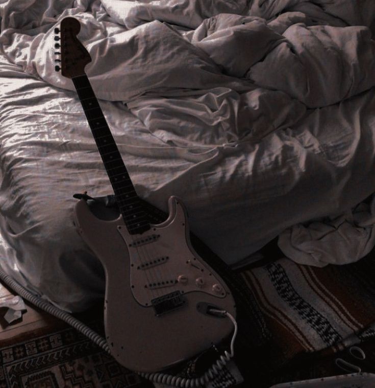 an electric guitar sitting on top of a bed