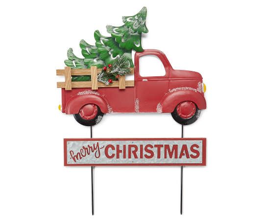 a red truck with a christmas tree in the back is on top of a sign