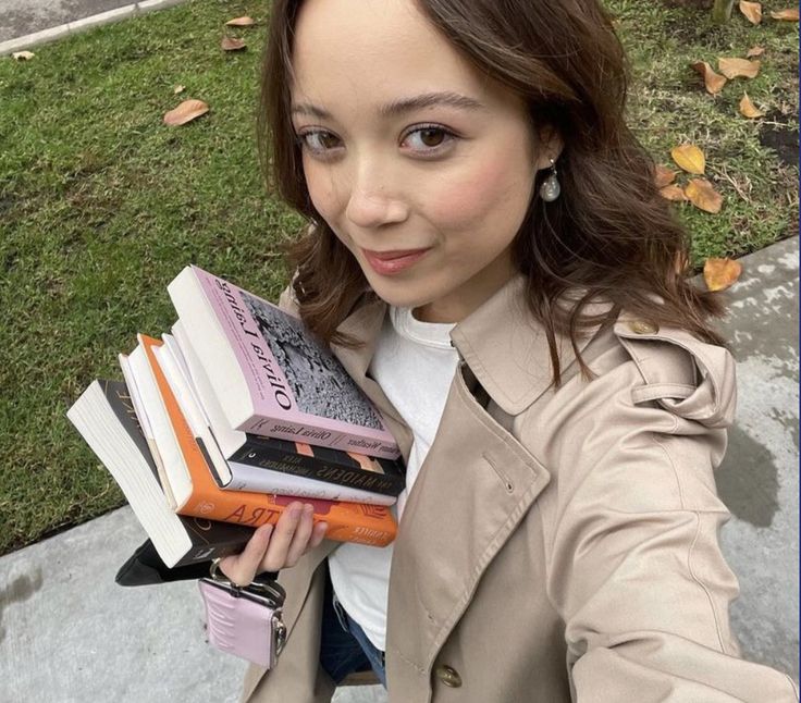 a woman is holding several books in her hands