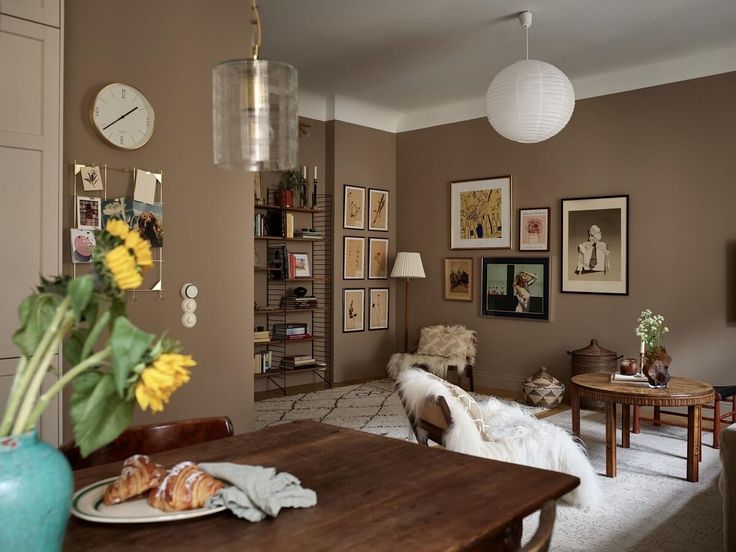 a living room filled with lots of furniture and pictures on the wall next to a wooden table