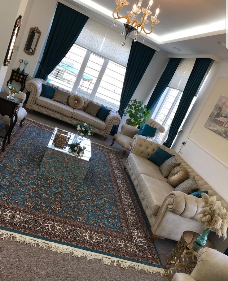 a living room with couches, chairs and rugs in front of two windows