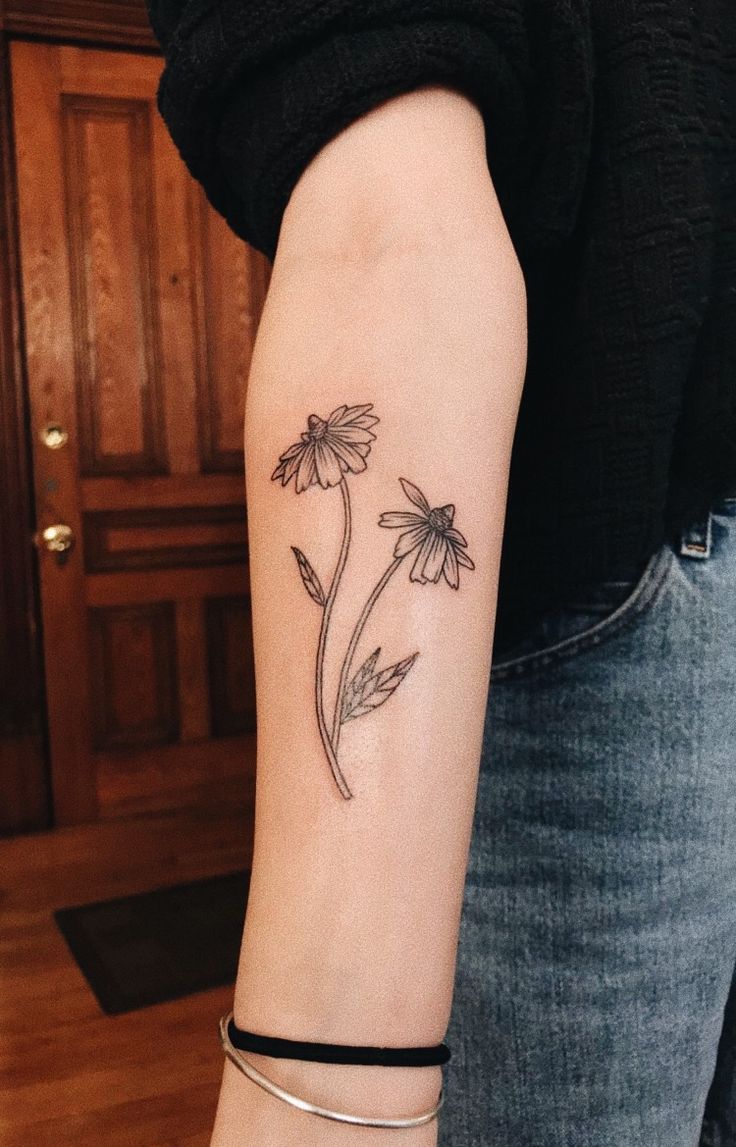 a woman's arm with a flower tattoo on the left side of her arm