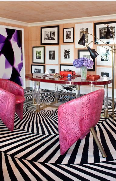 two pink chairs sitting on top of a black and white striped floor next to a table