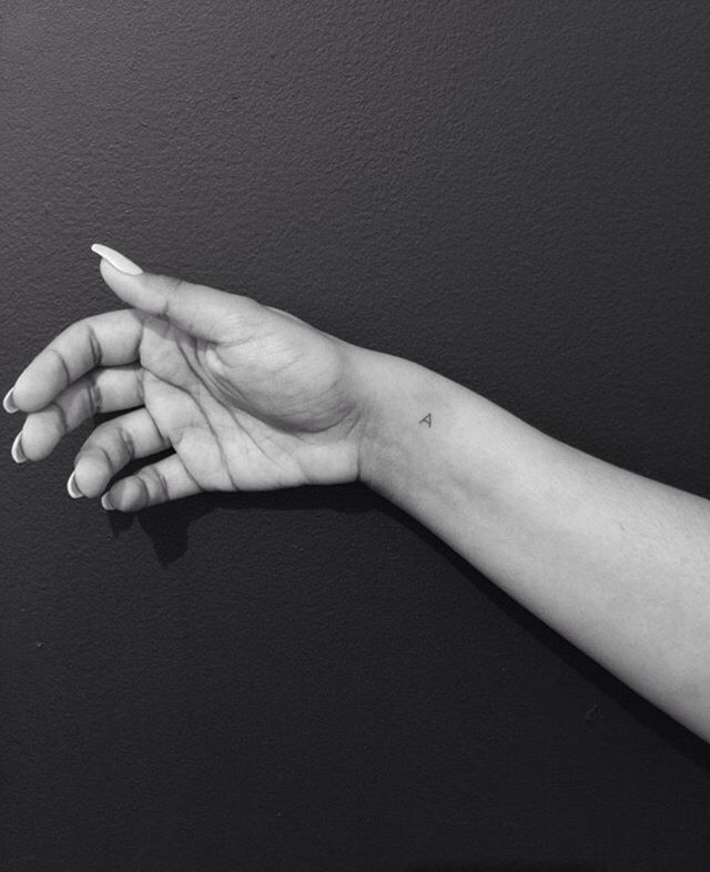 a person's hand with a small tattoo on it, against a black background