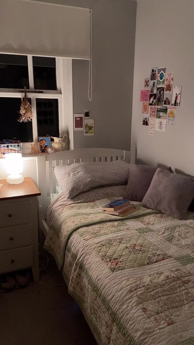 a bed sitting next to a window with a lamp on top of it in a bedroom