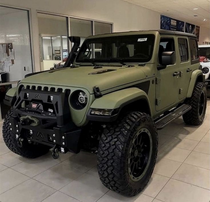 a green jeep is parked in a showroom