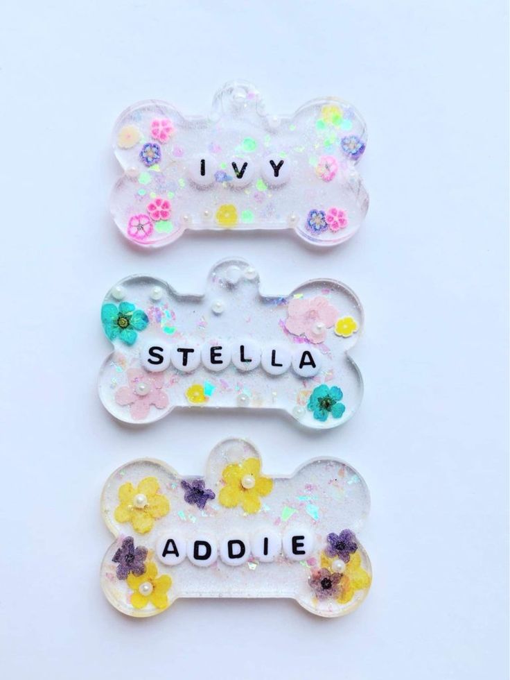 three dog bone shaped magnets with flowers and the words i love stella addie