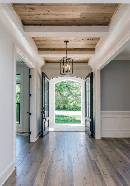 an empty hallway with wood flooring and white walls, leading to the front door