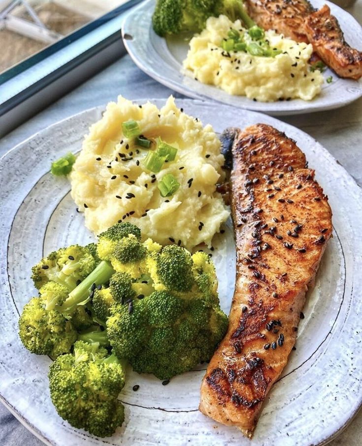 two plates with salmon, mashed potatoes and broccoli