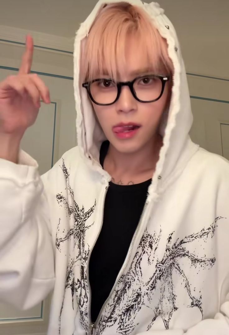 a person wearing glasses and a hoodie pointing to the side with their finger up