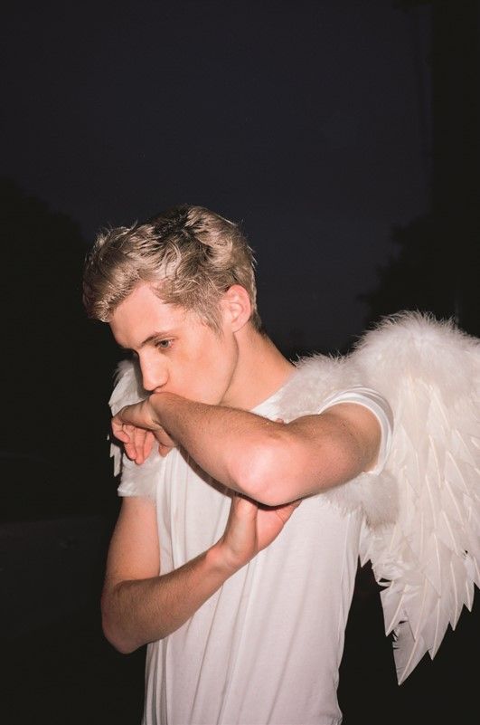 a man in white shirt with angel wings on his shoulder and arm around his chest