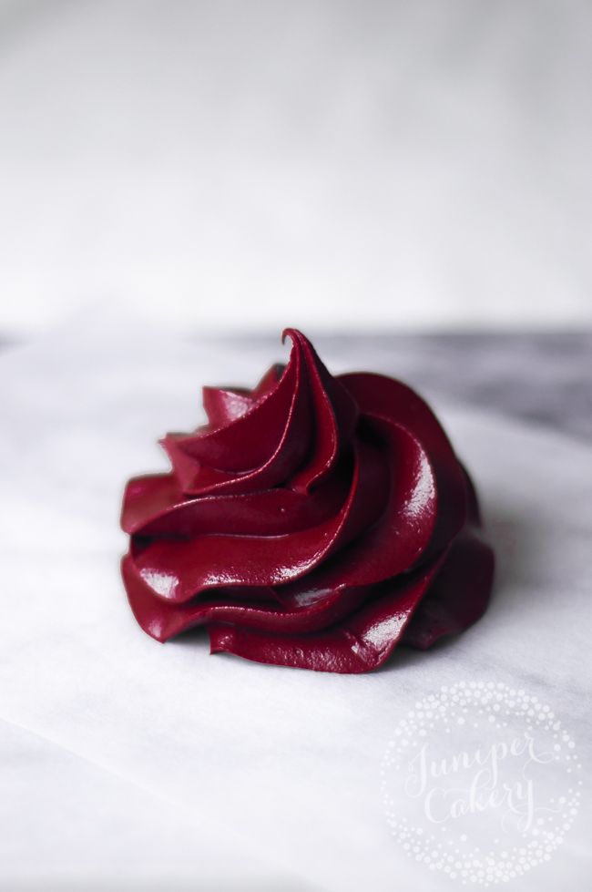 a close up of a piece of cake on a white surface with red icing