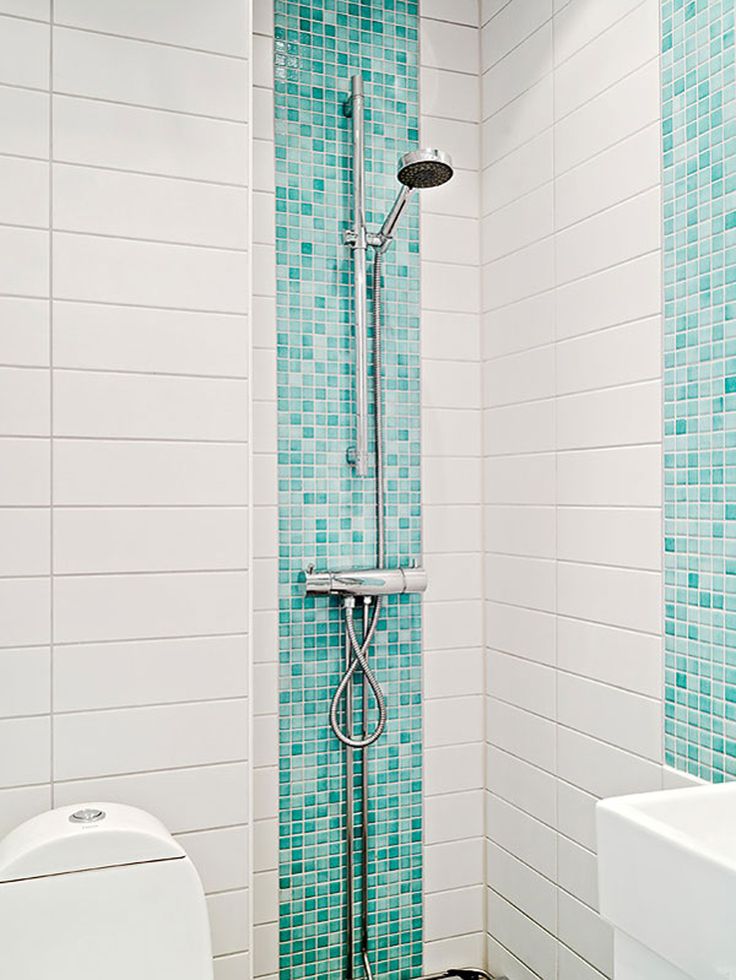 a white toilet sitting in a bathroom next to a walk in shower with blue tiles on the walls