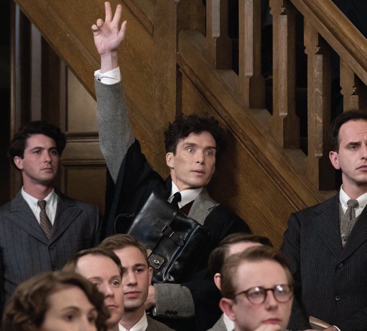 a group of men standing next to each other in front of a stair case holding their hands up