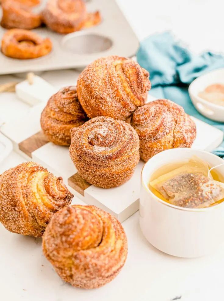 several pastries are sitting on a tray next to a cup of tea and sauce