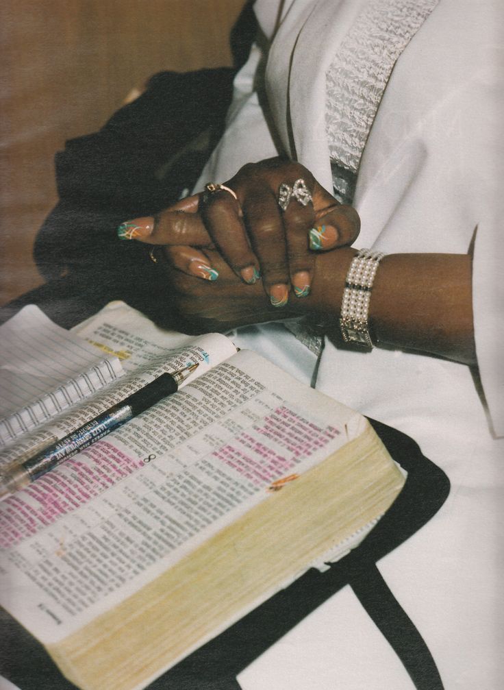 a woman holding her hands on top of an open bible