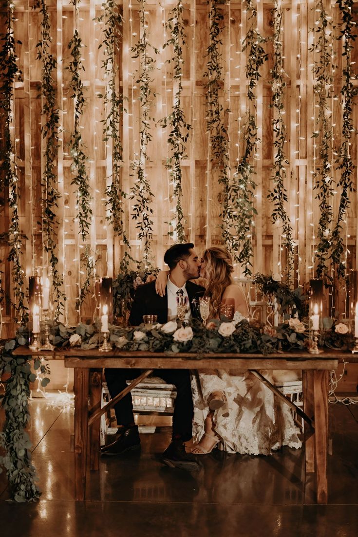 a man and woman sitting at a table in front of a backdrop with lights on it