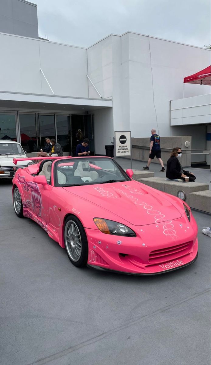 a pink sports car parked in front of a building