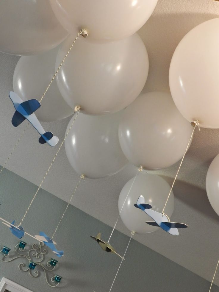 white and blue balloons hanging from the ceiling in a room with an airplane theme on it