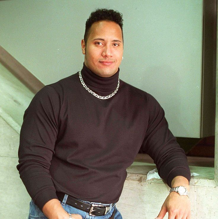 a man standing in front of some stairs wearing a black turtle neck sweater and jeans