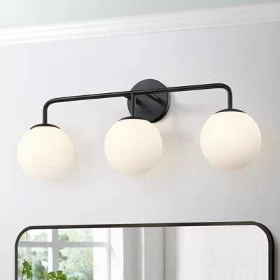 three light bathroom fixture in black finish with white glass globes on the top and bottom