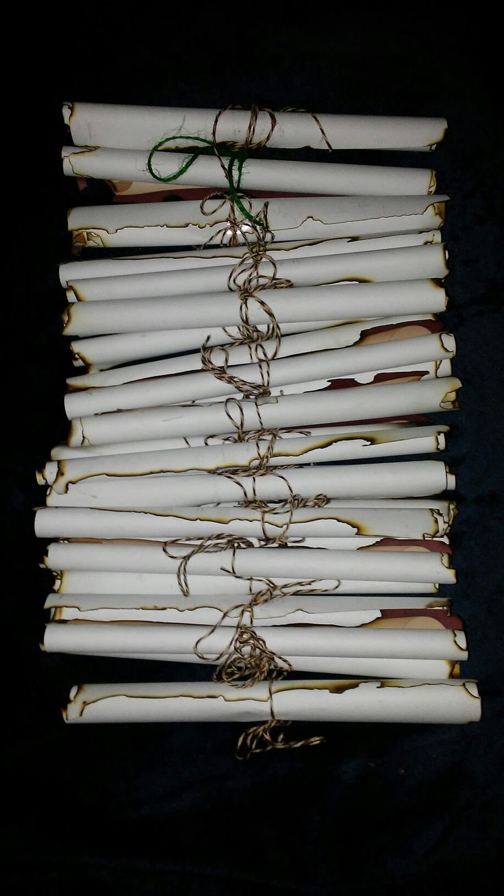 several white candles tied with twine and rope on a black tableclothed surface