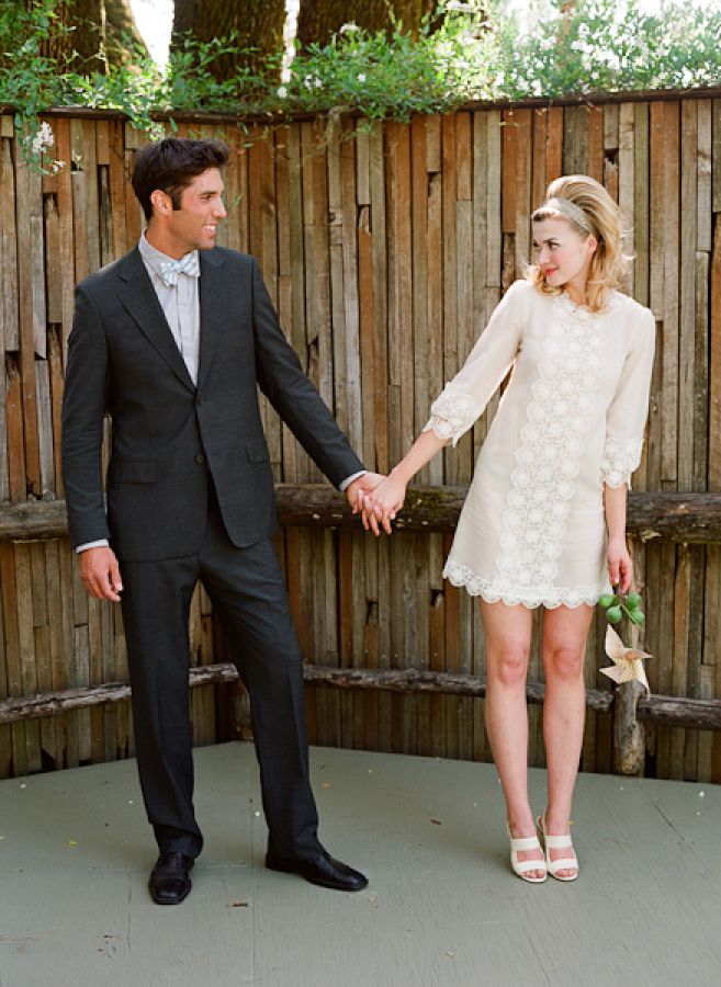 a man and woman holding hands in front of a wooden fence