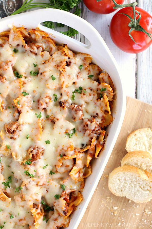 a casserole dish with cheese and meat in it next to bread on a cutting board