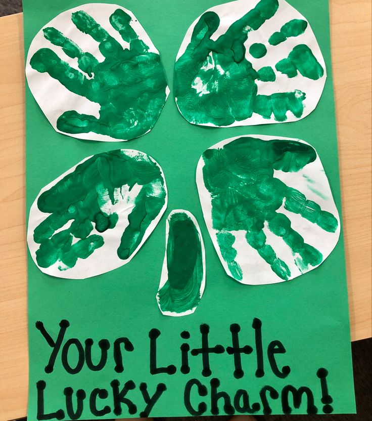 a green paper plate with four hand prints on it and the words your little lucky charm