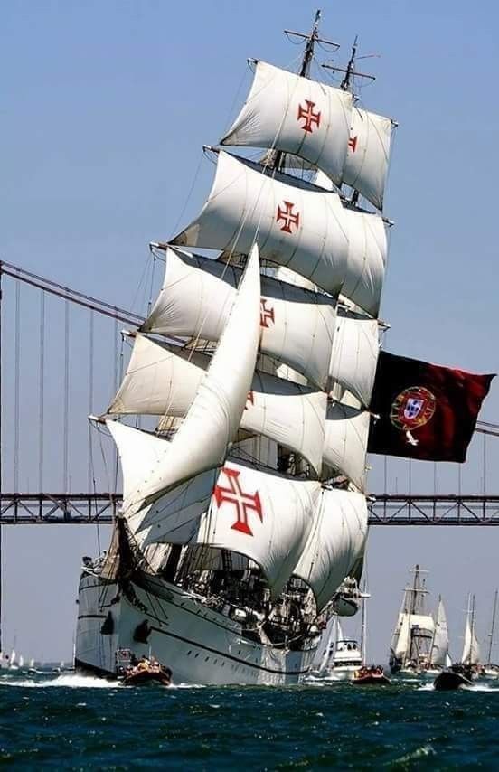 a large white sail boat sailing under a bridge