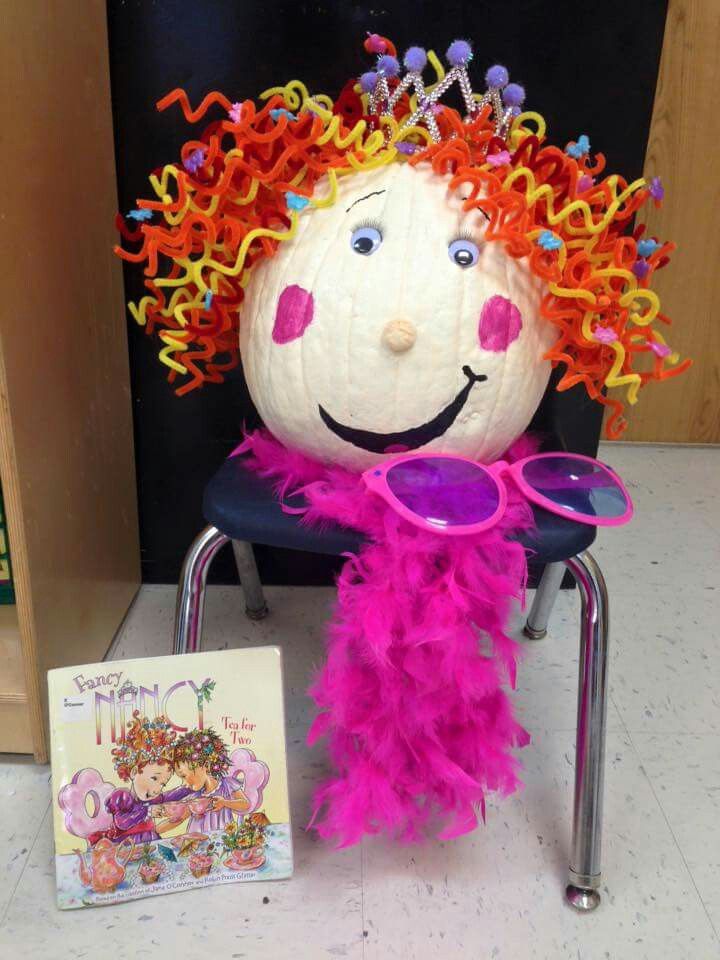 a pumpkin decorated like a child's face sitting on a chair next to a book