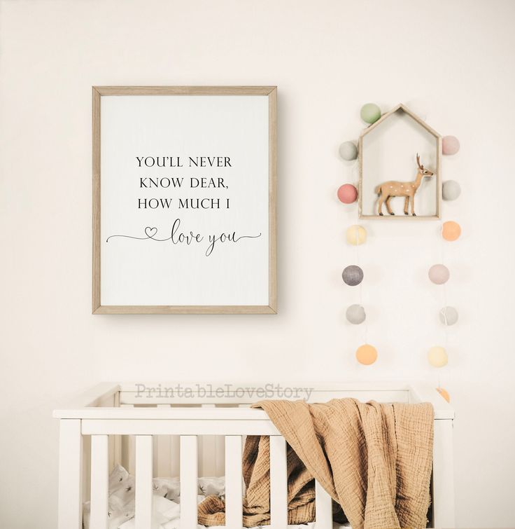 a baby's nursery with a framed quote on the wall and a crib