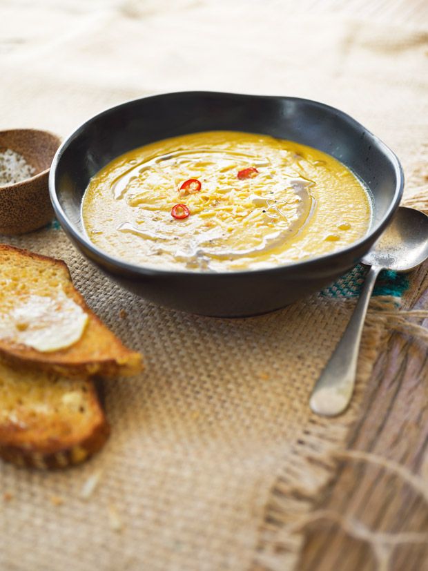 there is a bowl of soup and two slices of bread on the table next to it